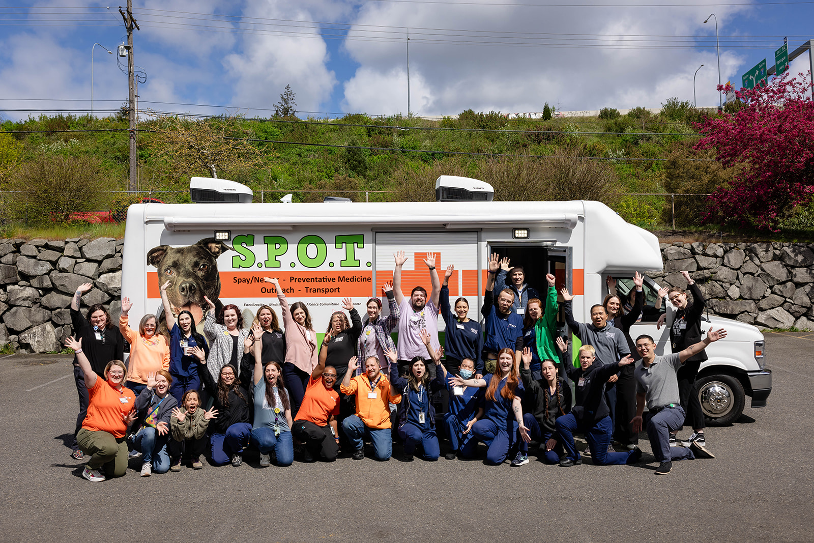 Shelter staff pose in front of S.P.O.T. with hands raised and big smiles